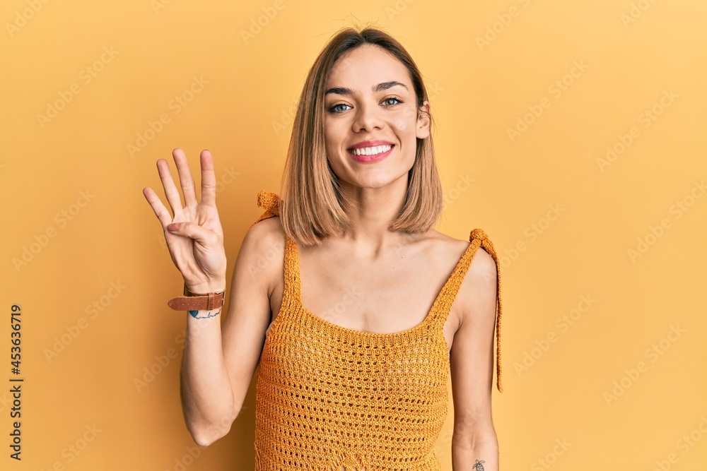 Young caucasian blonde woman wearing casual yellow t shirt showing and pointing up with fingers number four while smiling confident and happy. Young caucasian blonde woman wearing casual yellow t shirt showing and pointing up with fingers number four while smiling confident and happy.