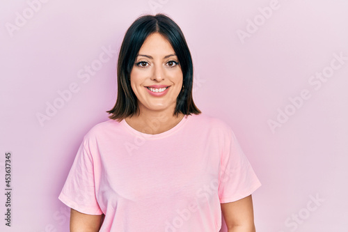 Young hispanic woman wearing casual pink t shirt with a happy and cool smile on face. lucky person.