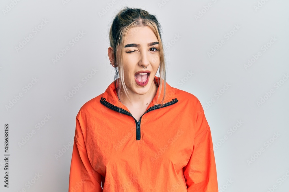 Young modern girl wearing sports sweatshirt winking looking at the camera with sexy expression, cheerful and happy face. Young modern girl wearing sports sweatshirt winking looking at the camera with sexy expression, cheerful and happy face.