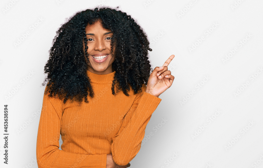 Young african american girl wearing casual clothes with a big smile on face, pointing with hand and finger to the side looking at the camera. Young african american girl wearing casual clothes with a big smile on face, pointing with hand and finger to the side looking at the camera.