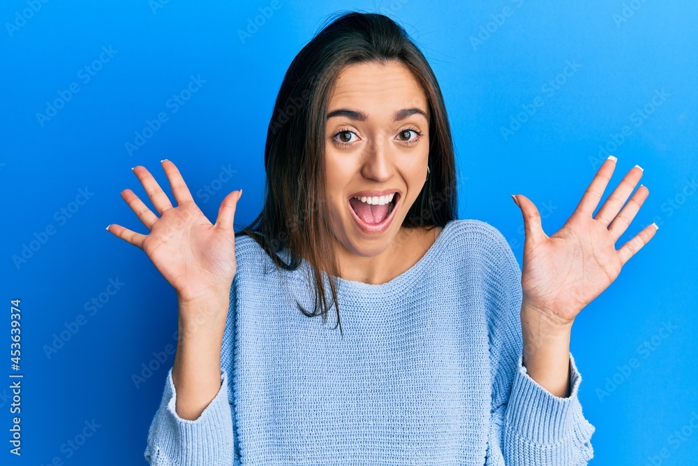 Young hispanic girl wearing casual clothes celebrating crazy and amazed for success with arms raised and open eyes screaming excited. winner concept Young hispanic girl wearing casual clothes celebrating crazy and amazed for success with arms raised and open eyes screaming excited. winner concept