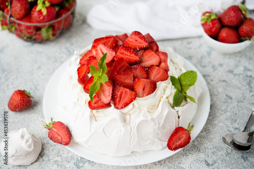 Pavlova cake with meringue and fresh strawberries on a light background