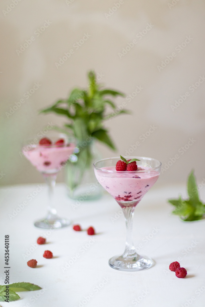 Raspberry dessert, cheesecake with fresh raspberries and butter cream mousse in glass.
