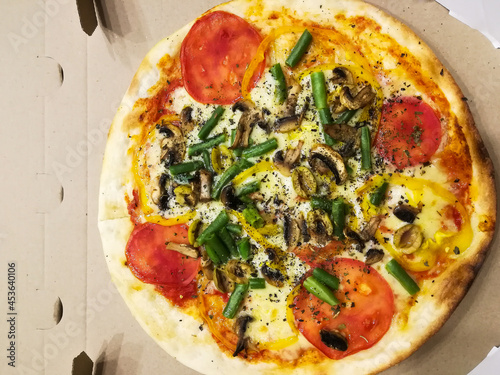 vegetarian homemade pizza with tomatoes, cheese, pepper, mushrooms and asparagus in a cardboard box