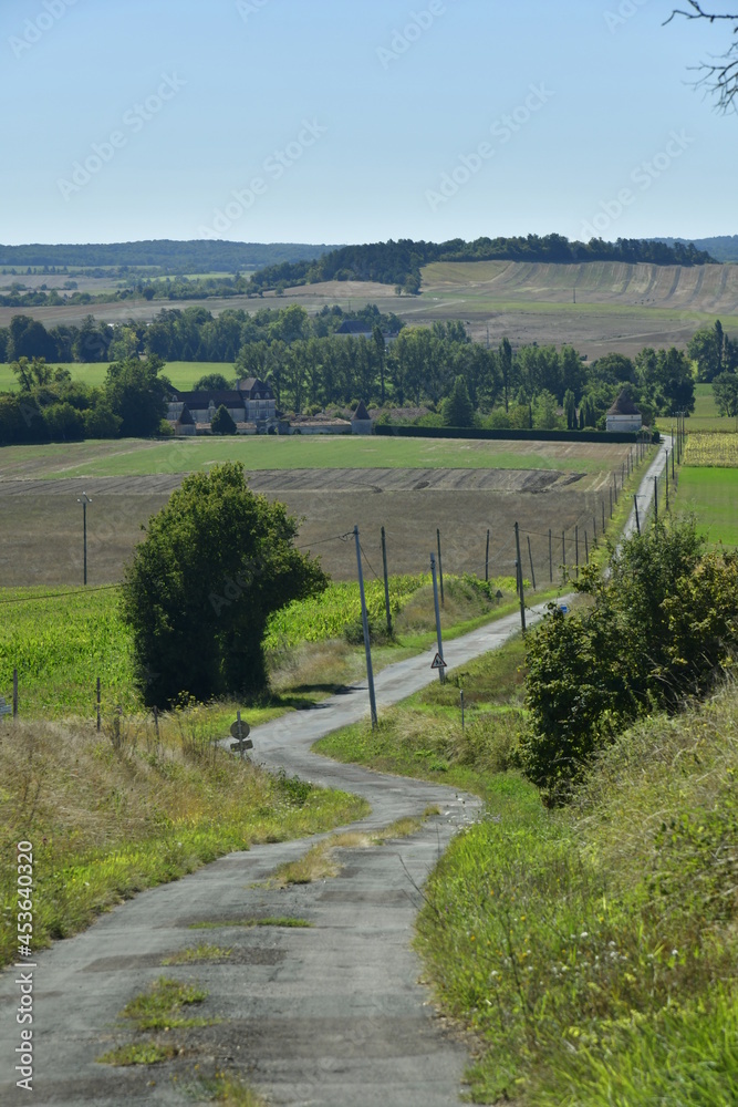 Route secondaire de campagne entre champs et prairie descendant la pente du Puy de Versac vers Goût-Rossignol au Périgord Vert