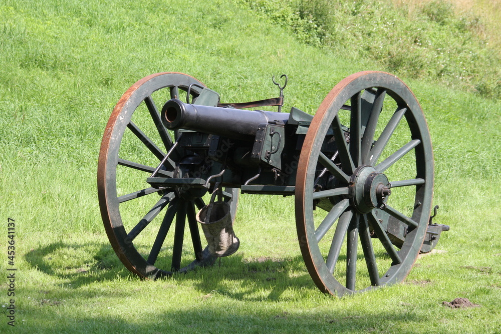 Historische  Kanone mit Speichenrädern auf der grünen Wiese