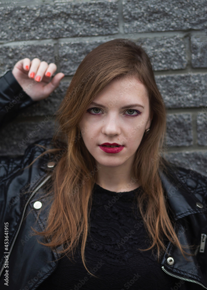 Sensual young woman in the leather jacket looking to camera. Close up outdoor portrait of gorgeous brunette girl in the evening city
