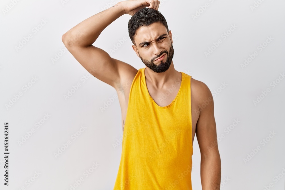 Young handsome man with beard standing over isolated background confuse and wonder about question. uncertain with doubt, thinking with hand on head. pensive concept.