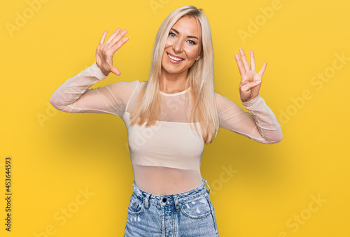 Young blonde woman wearing casual clothes showing and pointing up with fingers number nine while smiling confident and happy.