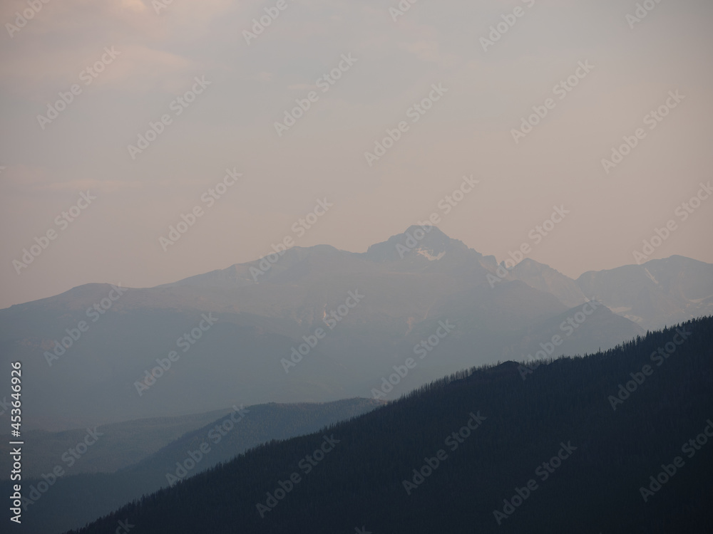 Obraz premium Rocky Mountains and forest trees shrouded in haze and smoke due to burning forest fires