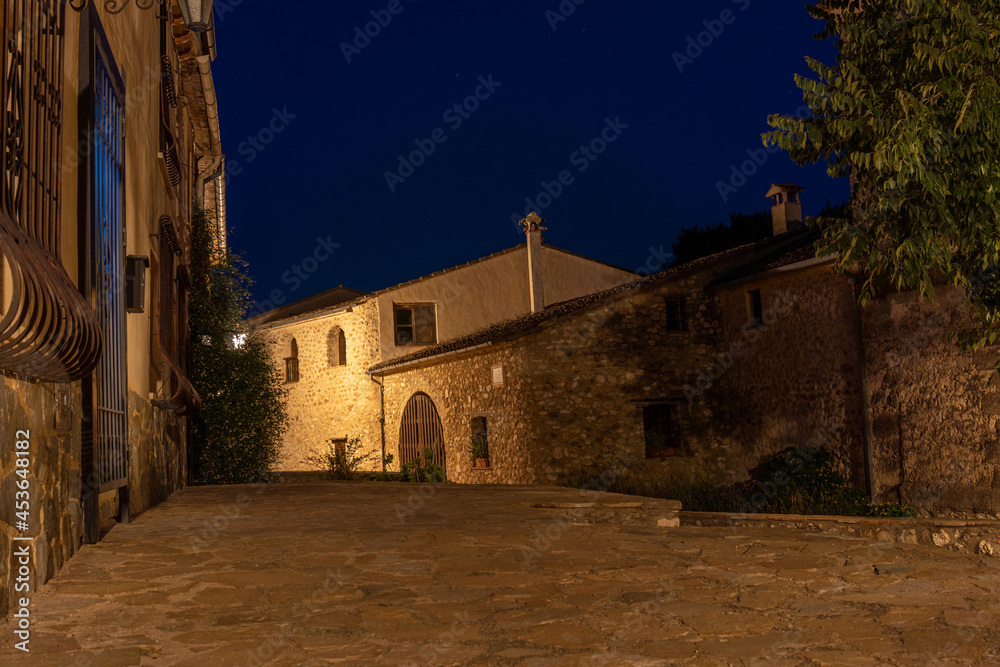 Old stone houses in a small town illuminated by streetlights at night. Old stone houses in a small town illuminated by streetlights at night.