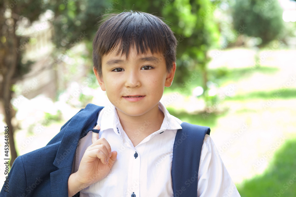 Happy asian boy in a uniform with a backpack outdoors. Back to school. Happy asian boy in a uniform with a backpack outdoors. Back to school.
