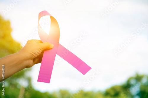 Pink plastic ribbon holding in hand of woman, blurred background, concept for supporting the breast cancer campaign of woman who is sick from breast cancer around the world.
