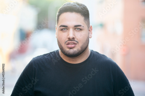 Fat latin man, looking at the camera. With a street in the background. Latins and curvy models concept.