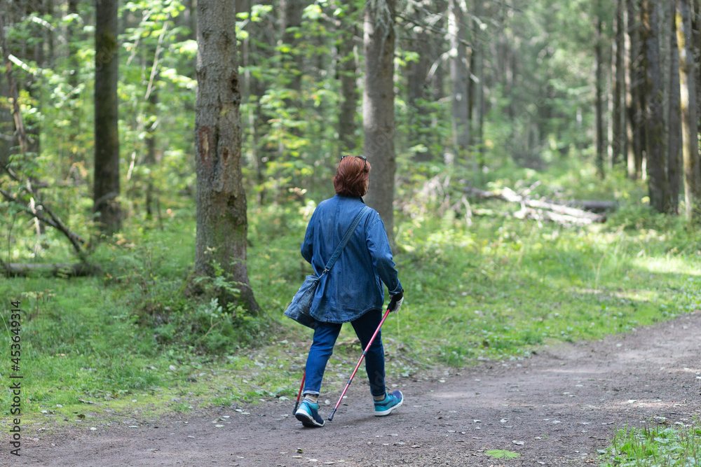 Nordic walking. A woman is engaged in Nordic walking in the park.