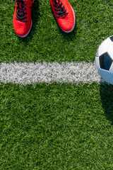 Soccer football background. Soccer ball and pair of football sports shoes on artificial turf soccer field. Top view