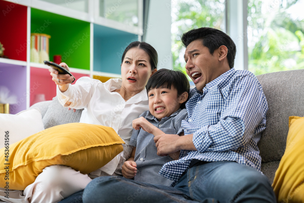 Happy asian parents sit on comfortable couch in living room with little kids watch TV enjoy home weekend enjoying movie Happy asian parents sit on comfortable couch in living room with little kids watch TV enjoy home weekend enjoying movie