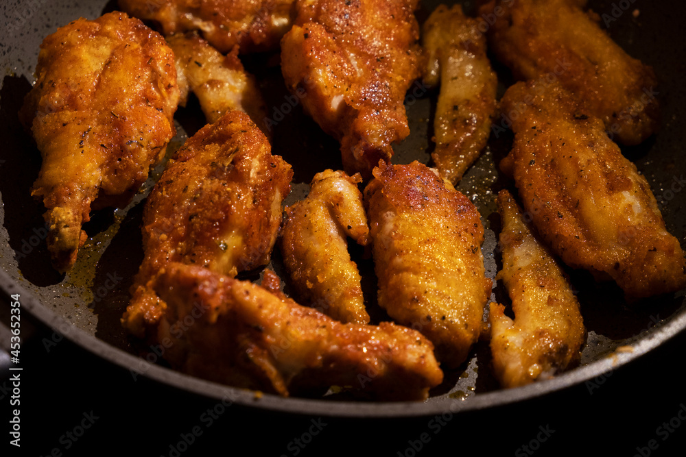 fried golden chicken wings in a pan on a black background