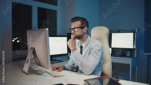 Concentrated young man working on computer while staying late in the office 