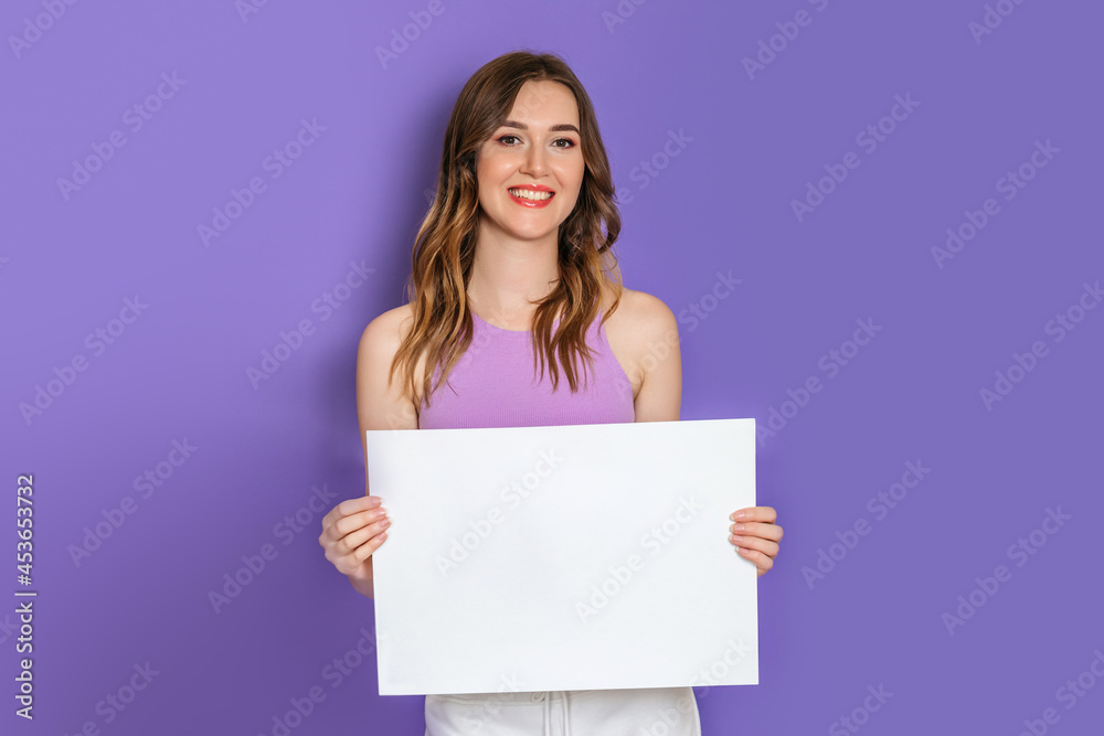 Young caucasian model holding a white square sheet of paper in hands smiling isolated on lilac background. Copy space Young caucasian model holding a white square sheet of paper in hands smiling isolated on lilac background. Copy space