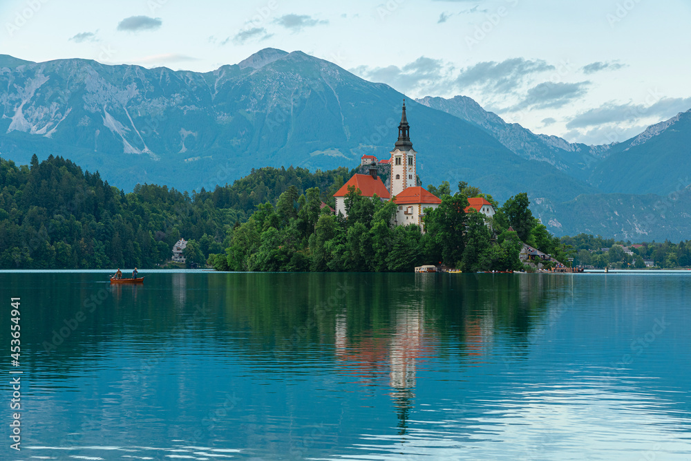 Bled lake view of island with church Assumption of Mary on beautiful lake with boat in Julian Alps, Slovenia