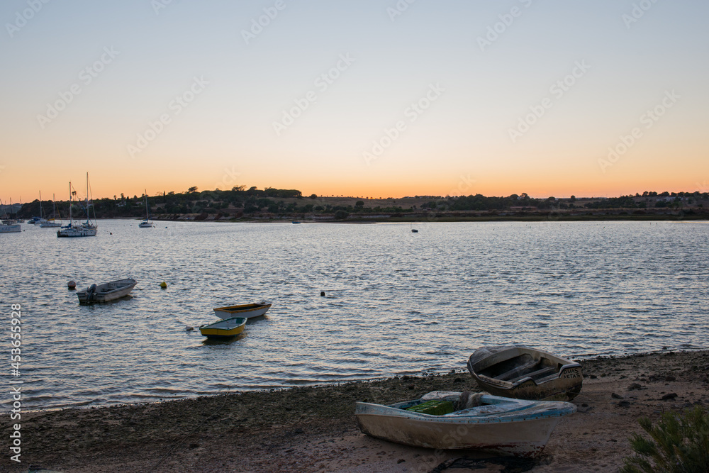 Beautiful sunset at Alvor harbour. Boats, calm water and orange sky. Portimao, Algarve, Portugal. Europe