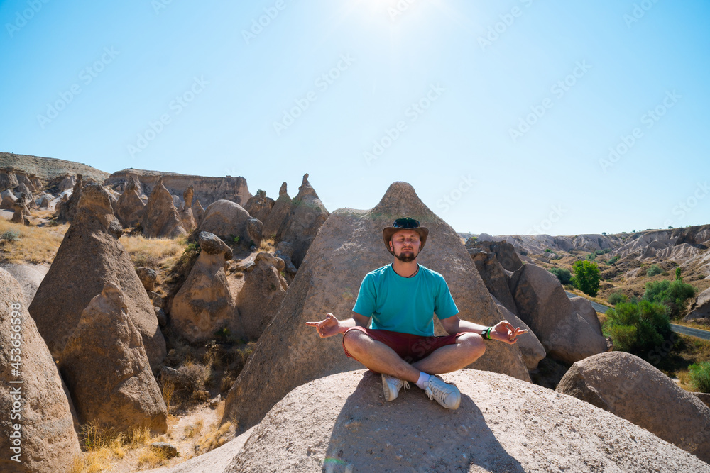 the tourist sits in the lotus position, meditates. unity with nature Devrent, Imaginary Valley full of unique rose rock formations in Cappadocia, Turkey. Travel and vacation concept.