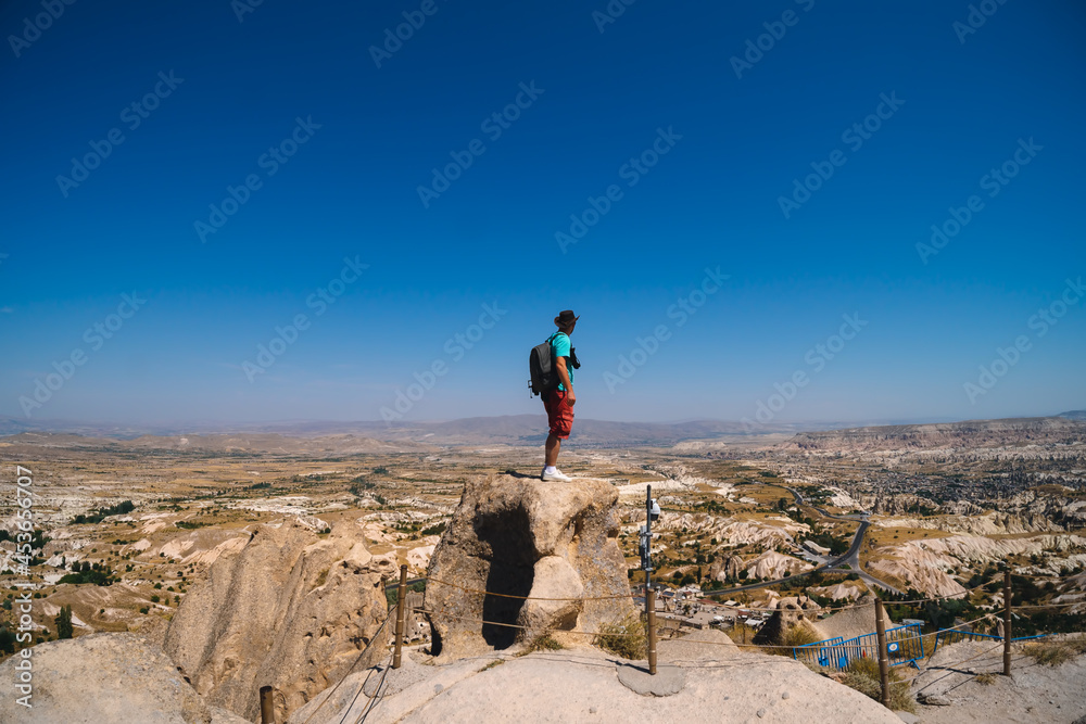 Uchisar Castle. Tourist at the top of the fortress, mountains, view of Cappadocia. Man photographer, male Traveler at Destinaton. Turkey Vacation and Tour Concept Summer day.