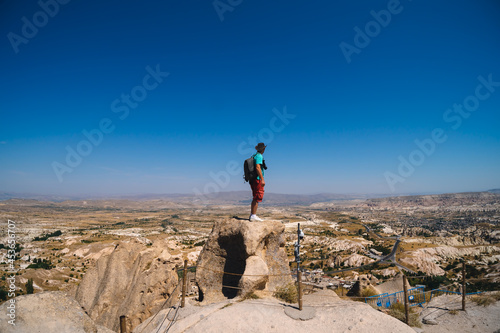 Uchisar Castle. Tourist at the top of the fortress, mountains, view of Cappadocia. Man photographer, male Traveler at Destinaton. Turkey Vacation and Tour Concept Summer day.