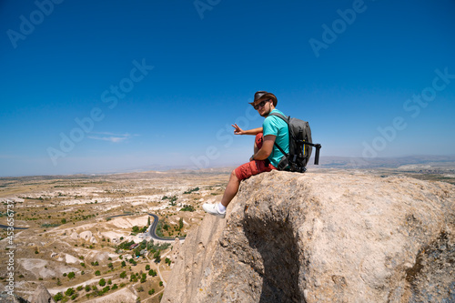 Uchisar Castle. Tourist at the top of the fortress  mountains  view of Cappadocia. Man photographer  male Traveler at Destinaton. Turkey Vacation and Tour Concept Summer day.