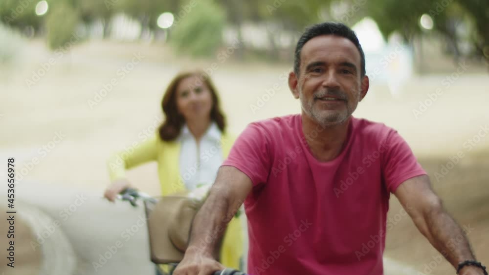 Front view of happy bearded man sitting on bike. Caucasian male person spending active weekend with wife in park and enjoying cycling. Sport, togetherness concept Front view of happy bearded man sitting on bike. Caucasian male person spending active weekend with wife in park and enjoying cycling. Sport, togetherness concept