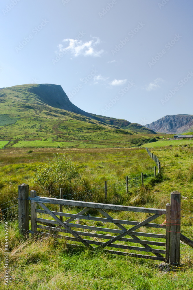 Snowdonia national park, Wales. Dramatic mountain landscape. Farm gate in the foreground with Y Garn mountain in the distance. Blue sky and copy space.