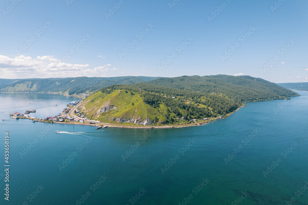 Fototapeta premium Lake Baikal is a marvelous blue jewel framed by scenic mountains and forests. Epic cinematic aerial view Lake Baikal. Aerial view of blue lake and green forests.