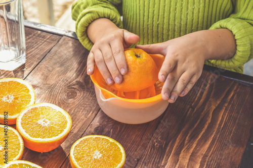 the girl child makes freshly squeezed orange juice on a manual juicer