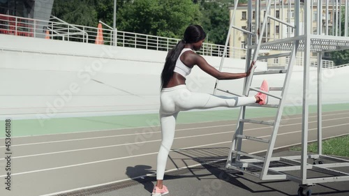 Confident young African woman in sports clothing doing stretching exercises