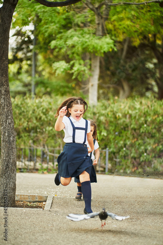 Spanish school girl running with pigeons in park