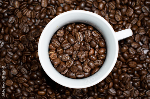 Cup of coffee full of coffee beans.