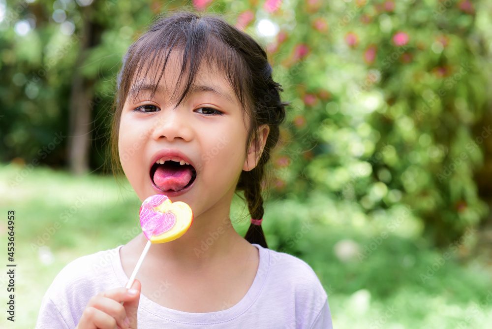 Portrait of toothless funny a little asian girl holding lollipops happily, eating sweets or lollipops will cause tooth decay. If you don't brush your teeth. Portrait of toothless funny a little asian girl holding lollipops happily, eating sweets or lollipops will cause tooth decay. If you don't brush your teeth.