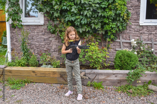 child girl with a rifle guards her own house photo without processing