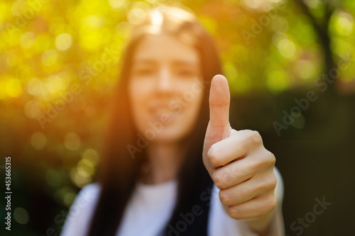 Young milennial brunette long hair woman is showing finger up sign during sunset. Positive agreement photo gesture. photo