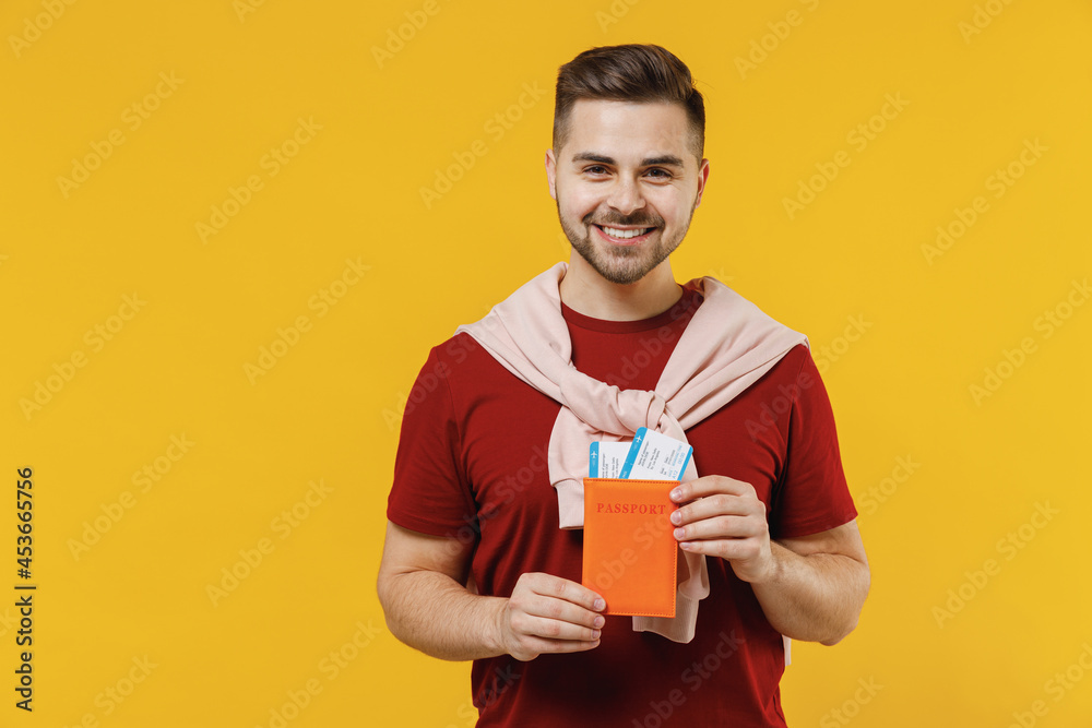 Traveler tourist man wear summer casual clothes hold passport tickets isolated on plain yellow color wall background studio. Passenger travel abroad on weekends getaway. Air flight journey concept Traveler tourist man wear summer casual clothes hold passport tickets isolated on plain yellow color wall background studio. Passenger travel abroad on weekends getaway. Air flight journey concept