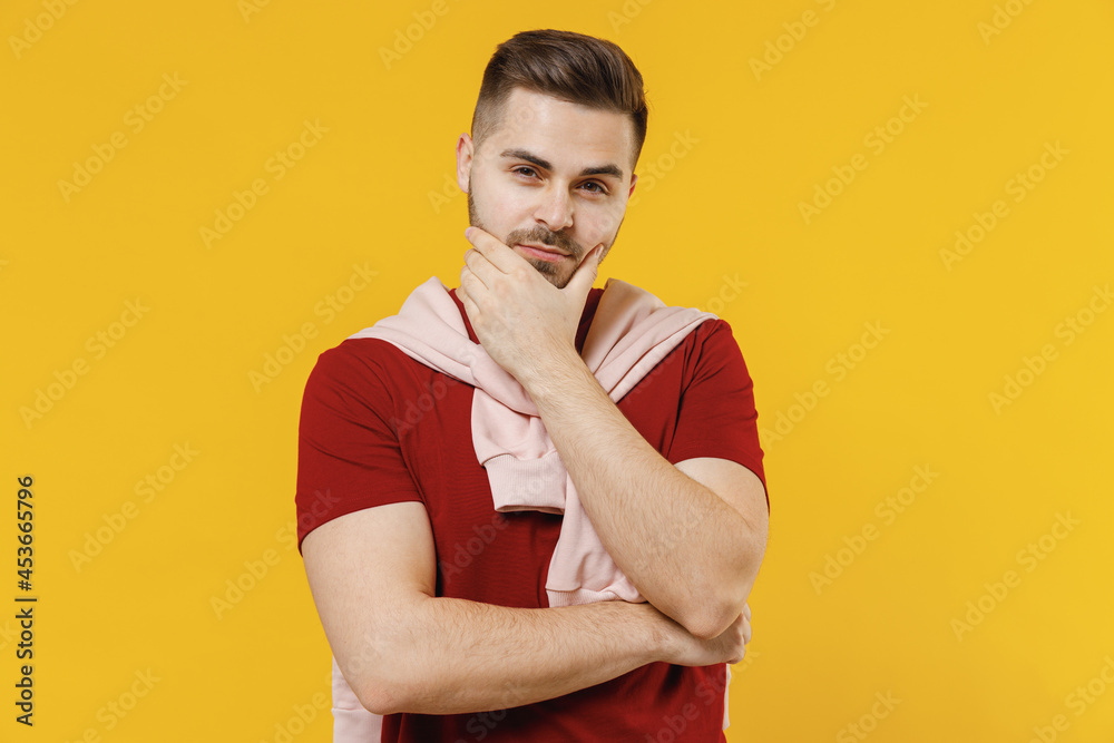 Smiling stylish cheerful happy young caucasian man wear red t-shirt casual clothes looking camera prop up chin isolated on plain yellow color wall background studio portrait. People lifestyle concept. Smiling stylish cheerful happy young caucasian man wear red t-shirt casual clothes looking camera prop up chin isolated on plain yellow color wall background studio portrait. People lifestyle concept.