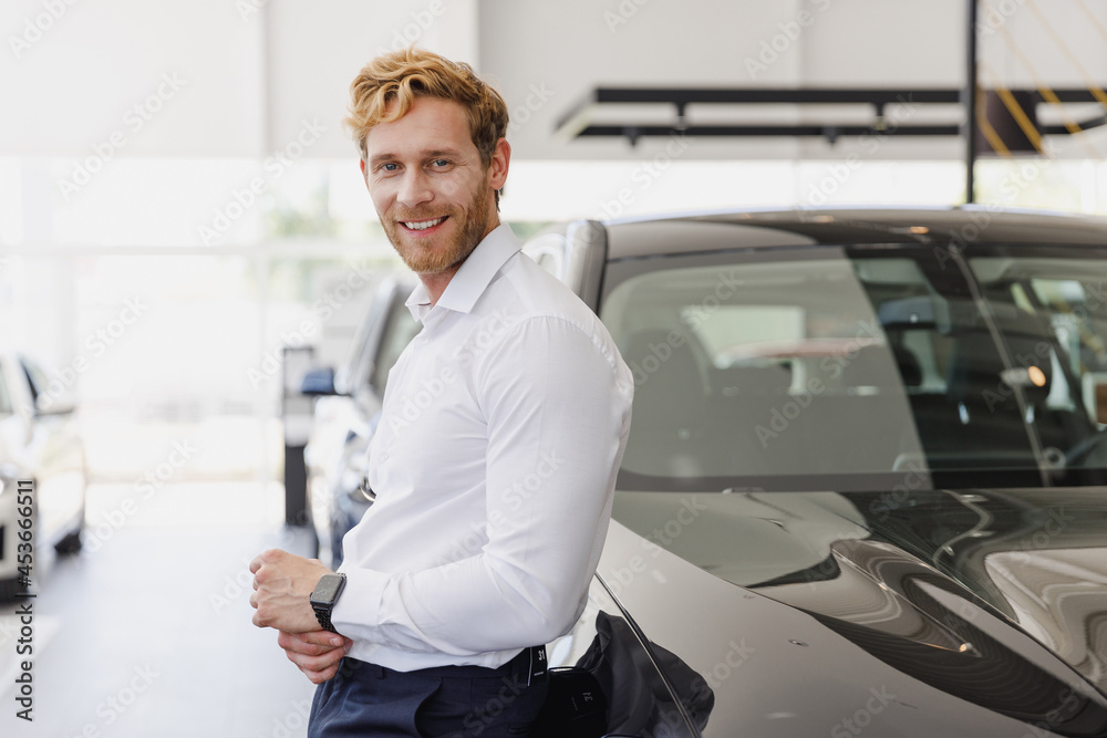 Confident minded man customer buyer businessman client wears white shirt chooses auto wants to buy new automobile in car showroom vehicle salon dealership store motor show indoor. Car sales concept Confident minded man customer buyer businessman client wears white shirt chooses auto wants to buy new automobile in car showroom vehicle salon dealership store motor show indoor. Car sales concept