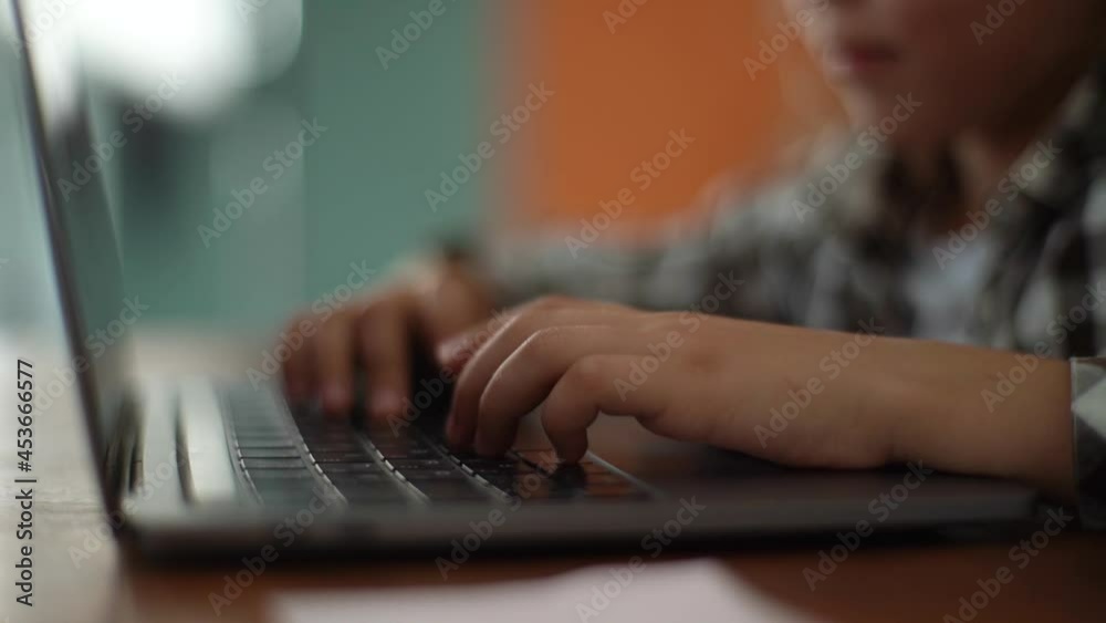 Close-up hands of unrecognizable smiling primary child school girl typing on laptop keyboard sitting at desk at home. Closeup of pupil schoolgirl e-learning online using computer, selective focus. Close-up hands of unrecognizable smiling primary child school girl typing on laptop keyboard sitting at desk at home. Closeup of pupil schoolgirl e-learning online using computer, selective focus.