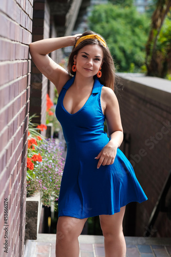An attractive young woman is posing leaning against a brick wall.
