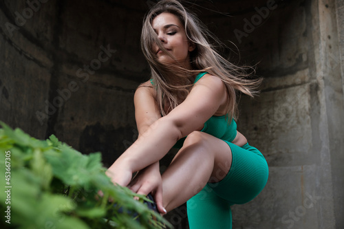 A young fitness woman is stretching in an urban environment.
