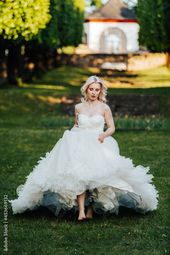beautiful, blond bride walking in the park with a big, white dress