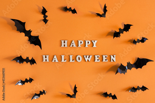 Halloween card with black bats on orange background. Banner for congratulations or invitation.