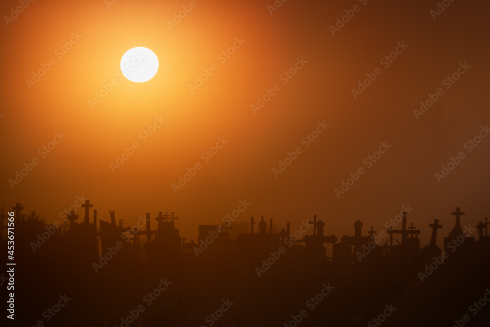 Obraz premium Silhouettes of the crosses of the Catholic cemetery in the fog in the early morning at dawn. Place for your text.