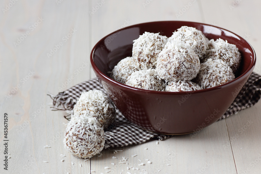 Vegan balls with dates, peanut butter and coconut on dark moody background, healthy protein homemade dessert for christmas holidays, closeup, copy space, vertical Vegan balls with dates, peanut butter and coconut on dark moody background, healthy protein homemade dessert for christmas holidays, closeup, copy space, vertical